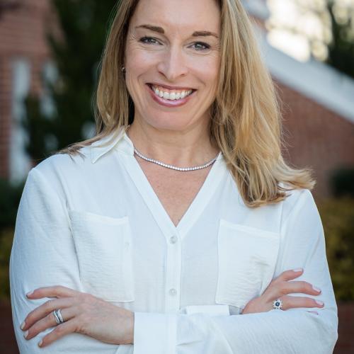 Headshot of woman in a white shirt and a building in the background